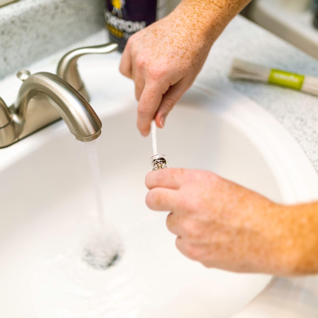 cleaning a drain pipe piece to unclog a bathroom drain, part of the phoenix plumbing services offered