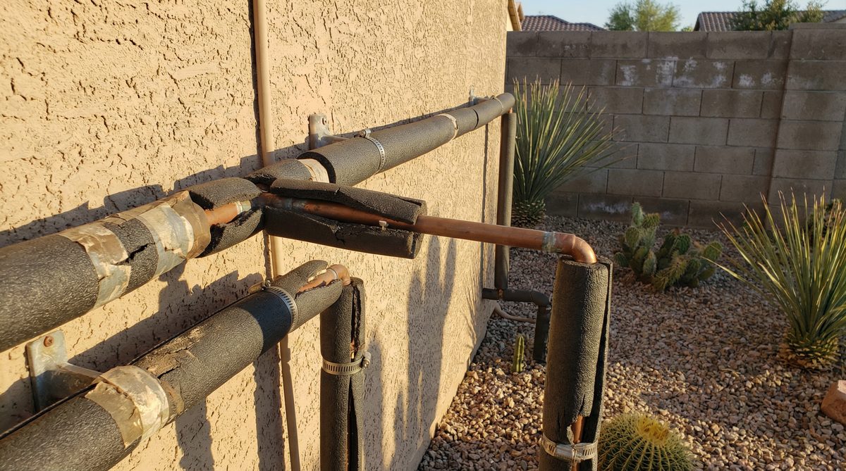 Insulated plumbing pipes on exterior of Arizona stucco home